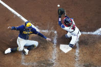 Milwaukee Brewers' Avisail Garcia (24) slides in to home as Atlanta Braves catcher Travis d'Arnaud (16) misses the tag during the fourth inning of Game 4 of a baseball National League Division Series, Tuesday, Oct. 12, 2021, in Atlanta. (AP Photo/John Bazemore)