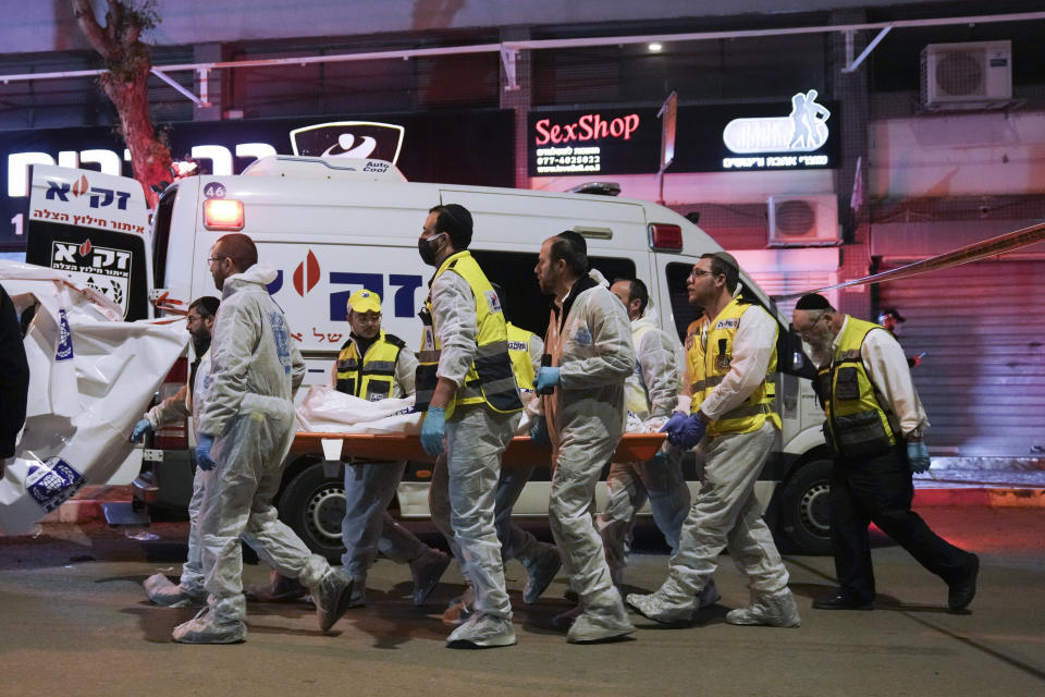 Israeli Zaka Rescue and Recovery team carry the body of a victim at the scene of shooting attack In Hadera, Israel, Sunday, March 27, 2022. A pair of gunmen killed two people and wounded four others in a shooting spree in central Israel before they were killed by police, according to police and medical officials. The identity of the gunmen was not immediately known, but police called them "terrorists," the term usually used for Arab assailants. (AP Photo/Ariel Schalit)