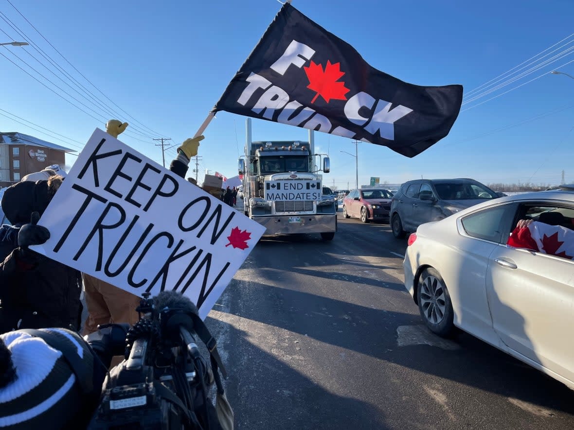 A trucking convoy drives along the Perimeter Highway in Winnipeg, Man., on Tuesday, Jan. 25, 2022 en route to Ottawa to protest a federal vaccine mandate. A bevy of supporters not with the convoy were also present. (Cameron MacIntosh/CBC - image credit)