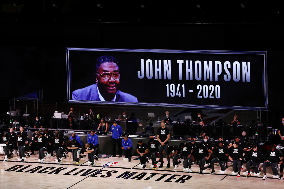 LAKE BUENA VISTA, FLORIDA - AUGUST 31: The Miami Heat and Milwaukee Bucks take a knee during the National Anthem and as a John Thompson tribute screen is displayed prior to Game One of the Eastern Conference Second Round during the 2020 NBA Playoffs at the Field House at ESPN Wide World Of Sports Complex on August 31, 2020 in Lake Buena Vista, Florida. NOTE TO USER: User expressly acknowledges and agrees that, by downloading and or using this photograph, User is consenting to the terms and conditions of the Getty Images License Agreement. (Photo by Mike Ehrmann/Getty Images)