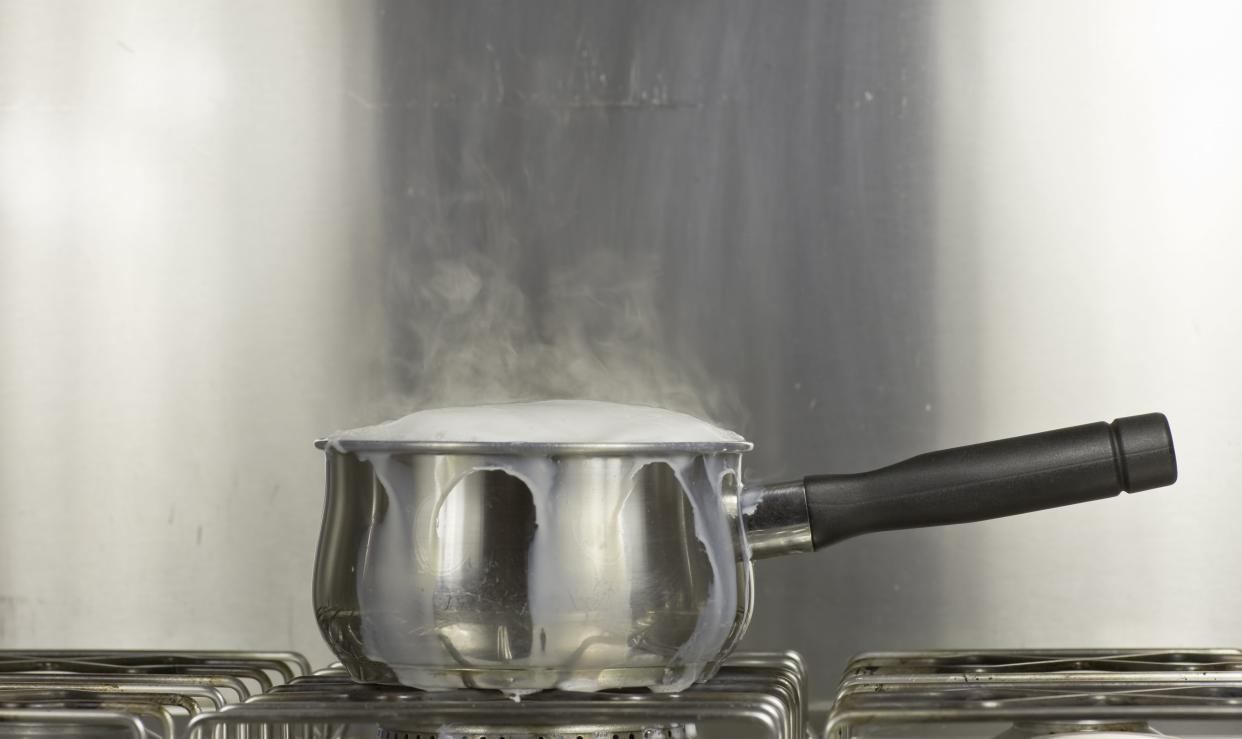 Steel and monochromatic study of milk boiling over on a gas hob.