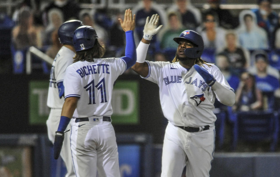 Toronto Blue Jays' Bo Bichette (11) and Vladimir Guerrero Jr. celebrate after scoring on Randal Grichuk's three-run double off Los Angeles Angels' Jose Quintana during the second inning of a baseball game Saturday, April 10, 2021, in Dunedin, Fla. (AP Photo/Steve Nesius)