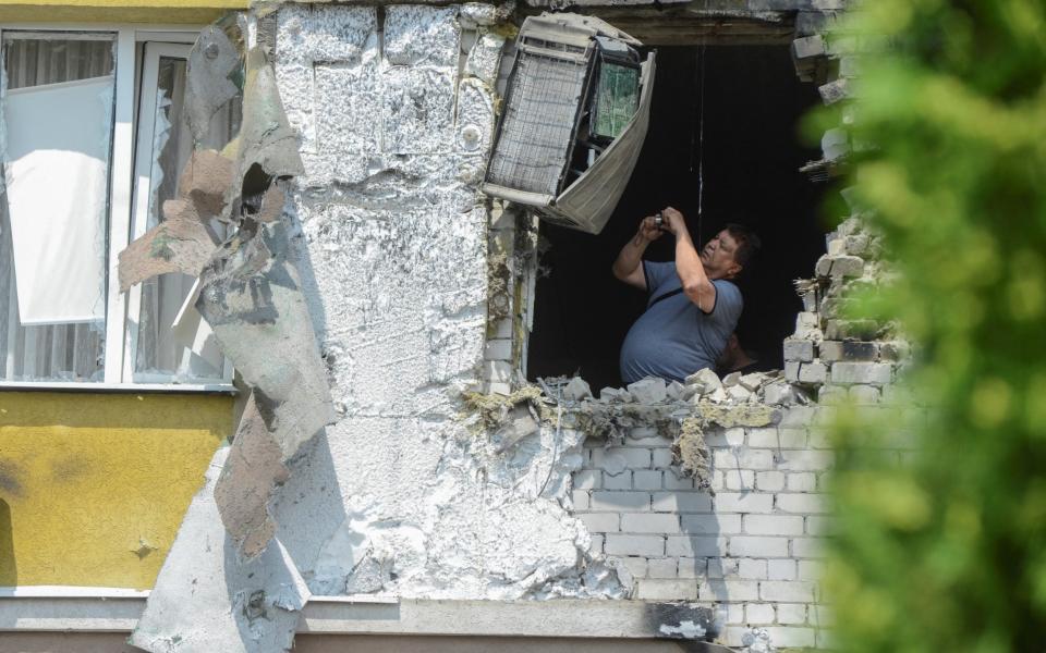 A man takes pictures inside a damaged multi-storey apartment block following a reported drone attack in Voronezh, Russia - VLADIMIR LAVROV/REUTERS