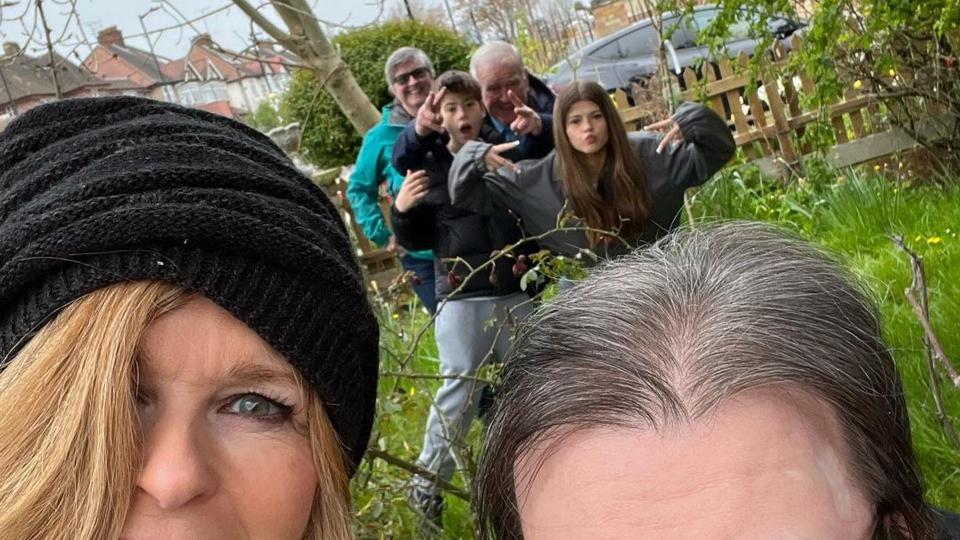 Kate Garraway smiling alongside her husband Derek Draper and her family