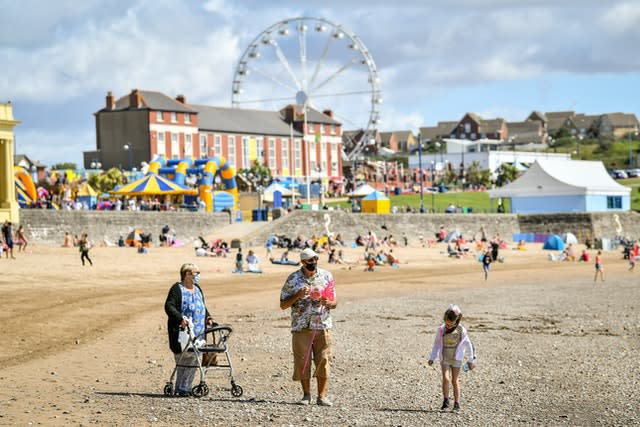 People walk along Barry Island beach in Wales in early August