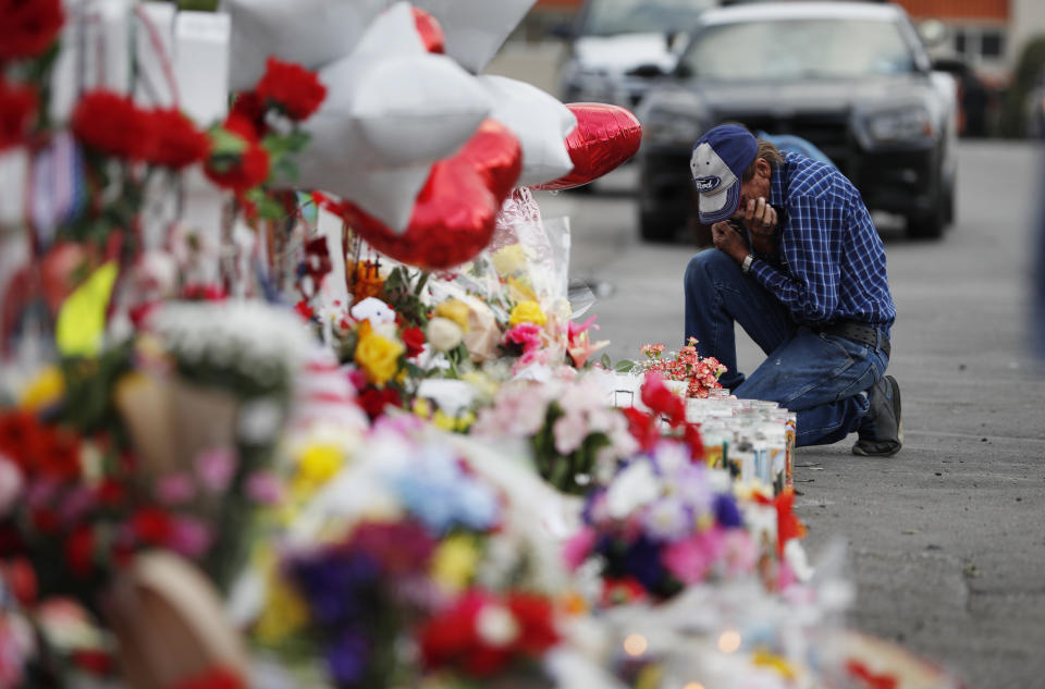 A man cries beside a cross at a makeshift memorial near the scene of a mass shooting at a shopping complex Tuesday, Aug. 6, 2019, in El Paso, Texas. The border city jolted by a weekend massacre at a Walmart absorbed more grief Monday as the death toll climbed and prepared for a visit from President Donald Trump over anger from El Paso residents and local Democratic leaders who say he isn't welcome and should stay away. (AP Photo/John Locher)