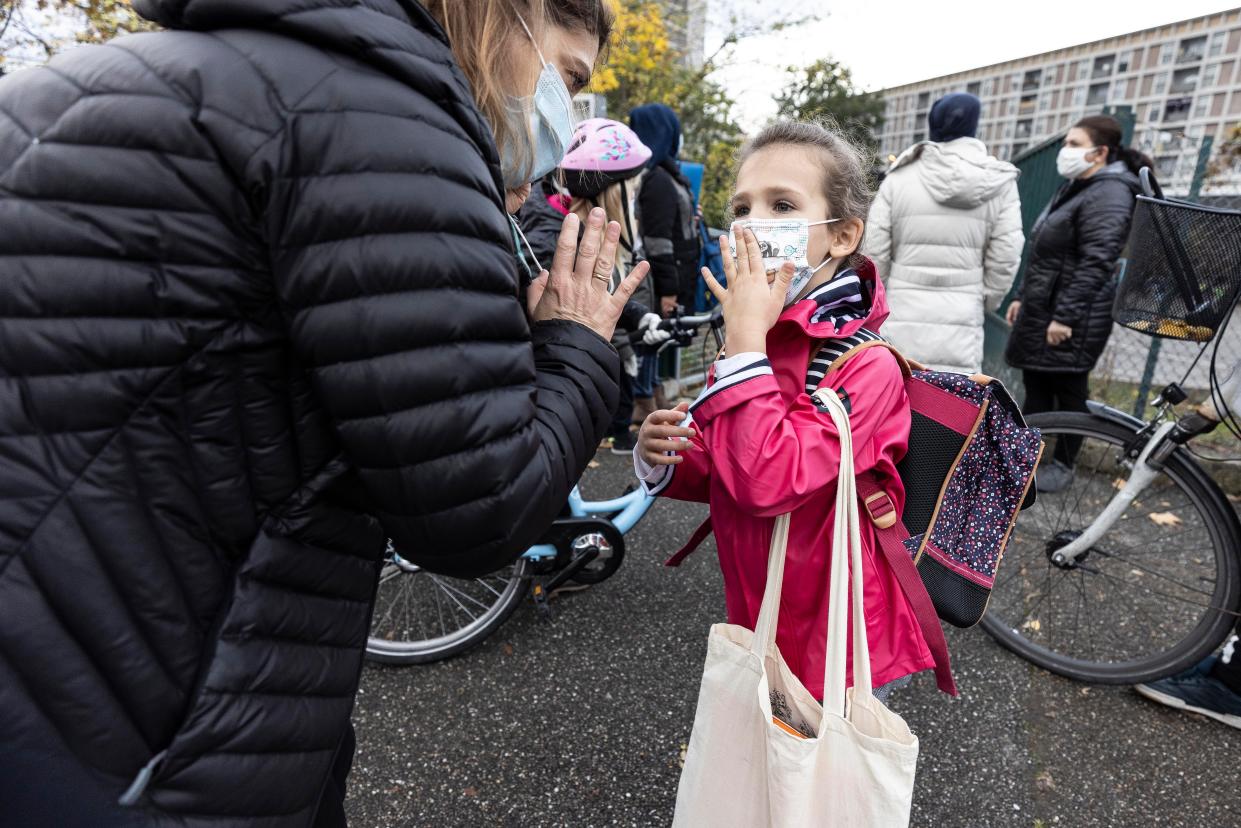 A mother and her daughter wave goodbye as school resumes with new sanitary precautions during the lockdown on Monday, Nov. 2, 2020, in Strasbourg, eastern France. France went into shutdown mode Friday, closing non-essential businesses and ordering residents to stay within one kilometer (half-mile) from home unless they're going to school or have an exceptional reason to leave. Permission slips are required to leave home, and violators are fined 135 euros.