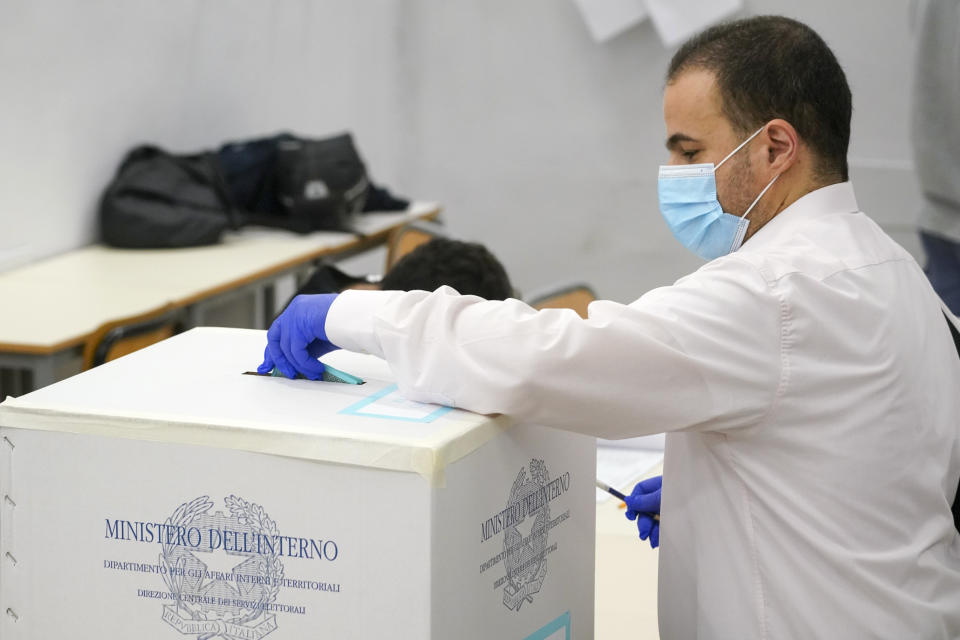 A man casts his ballot at a polling station, in Rome, Sunday, Sept. 20, 2020. On Sunday and Monday Italians are called to vote nationwide in a referendum to confirm a historical change to the country's constitution to drastically reduce the number of Members of Parliament from 945 to 600. Eighteen million of Italian citizens will also vote on Sunday and Monday to renew local governors in seven regions, along with mayors in approximately 1,000 cities. (AP Photo/Andrew Medichini)