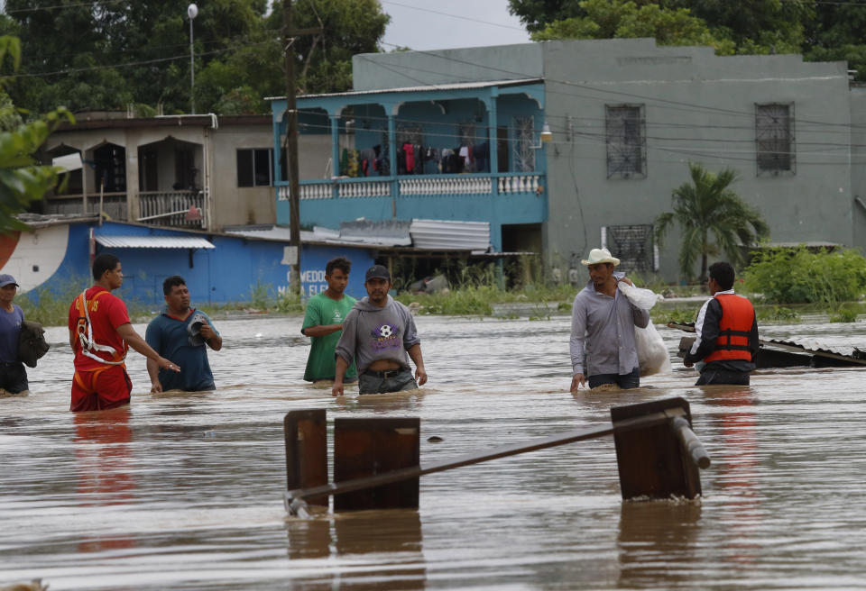 Men wade through a street flooded after the passing of Hurricane Iota in La Lima, Honduras, Wednesday, Nov. 18, 2020. Iota flooded stretches of Honduras still underwater from Hurricane Eta, after it hit Nicaragua Monday evening as a Category 4 hurricane and weakened as it moved across Central America, dissipating over El Salvador early Wednesday. (AP Photo/Delmer Martinez)