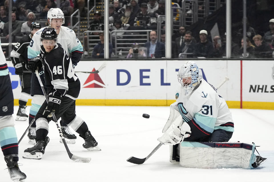 Seattle Kraken goaltender Philipp Grubauer, right, deflects a shot as Los Angeles Kings center Blake Lizotte, center, and defenseman Will Borgen watch during the second period of an NHL hockey game Wednesday, April 3, 2024, in Los Angeles. (AP Photo/Mark J. Terrill)