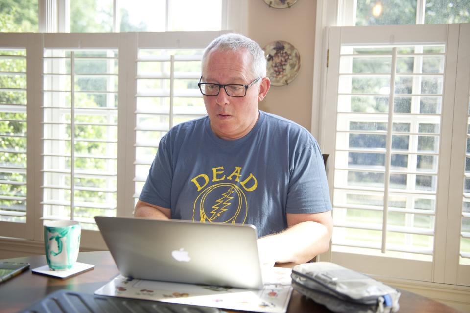 Michael Caputo sits while working on a laptop wearing a Grateful Dead T-shirt