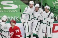 Detroit Red Wings right wing Richard Panik (24) skates past as Dallas Stars' Sami Vatanen (45), Jamie Oleksiak (2), Denis Gurianov (34) and Tanner Kero (64) celebrate a goal scored by Oleksiak in the second period of an NHL hockey game in Dallas, Tuesday, April 20, 2021. (AP Photo/Tony Gutierrez)