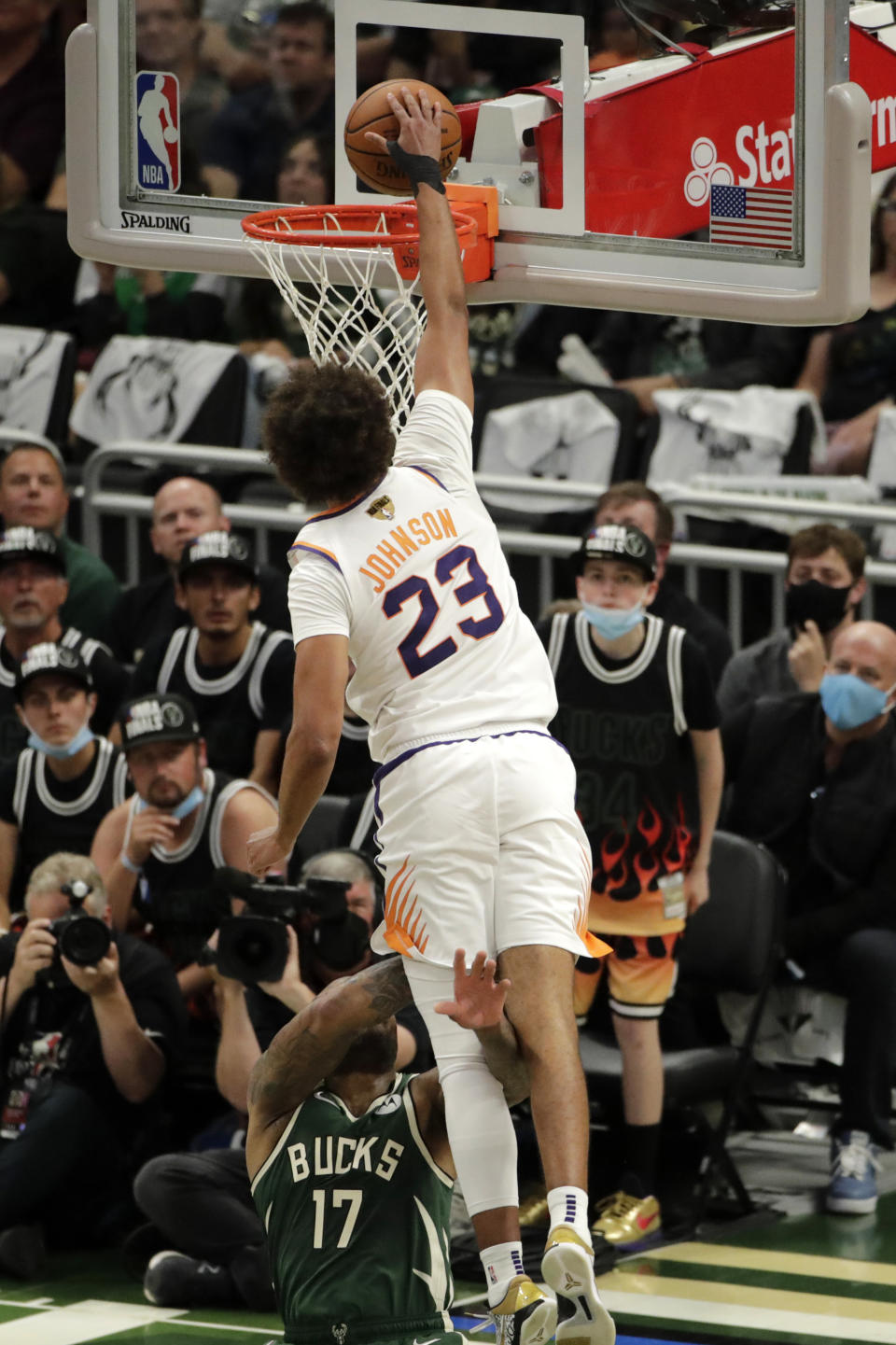 Phoenix Suns' Cameron Johnson (23) dunks as he's fouled by Milwaukee Bucks' P.J. Tucker (17) during the second half of Game 3 of basketball's NBA Finals, Sunday, July 11, 2021, in Milwaukee. (AP Photo/Aaron Gash)