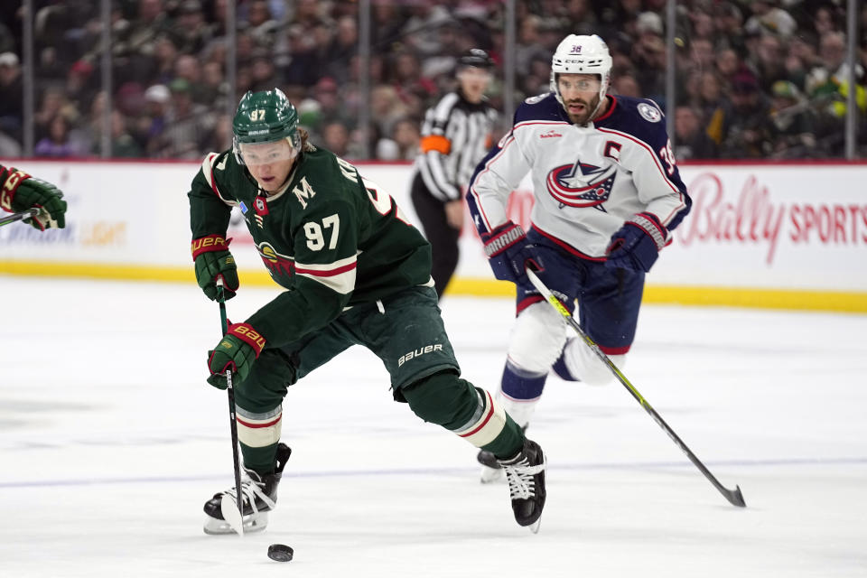 Minnesota Wild left wing Kirill Kaprizov (97), left, skates with the puck against Columbus Blue Jackets center Boone Jenner (38) during the first period of an NHL hockey game Sunday, Feb. 26, 2023, in St. Paul, Minn. (AP Photo/Abbie Parr)