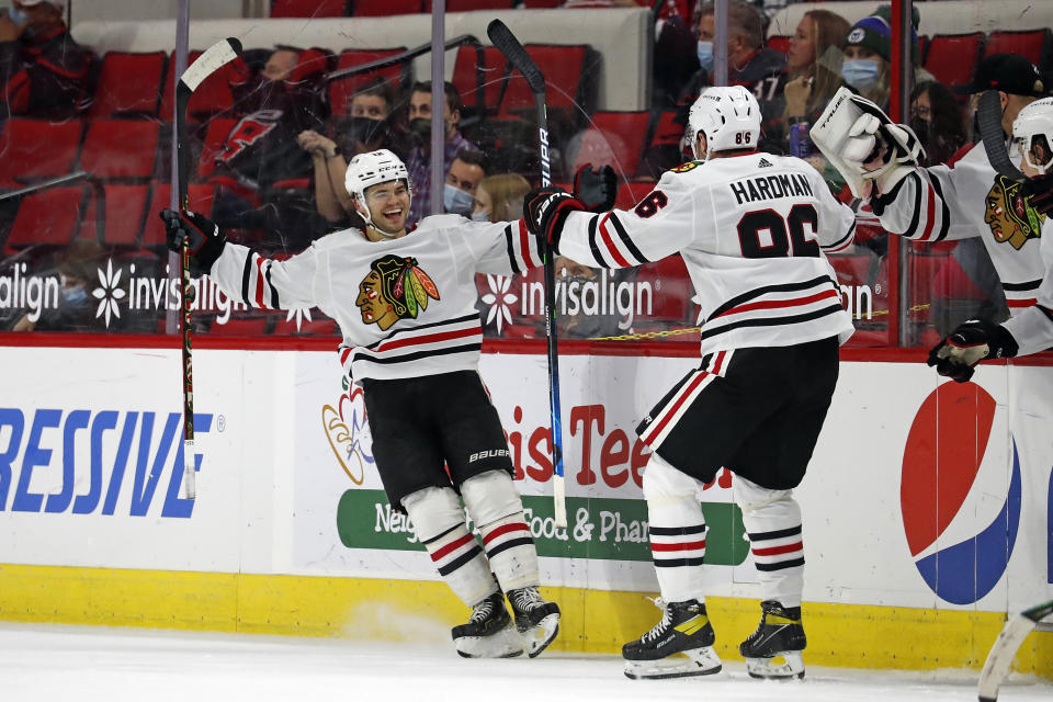 Chicago Blackhawks' Alex DeBrincat (12) celebrates his overtime goal with Mike Hardman (86) during an NHL hockey game against the Carolina Hurricanes in Raleigh, N.C., Thursday, May 6, 2021. (AP Photo/Karl B DeBlaker)