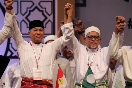 UMNO President Ahmad Zahid Hamidi and PAS President Hadi Awang hold hands during Ummah Unity Gathering in Kuala Lumpur