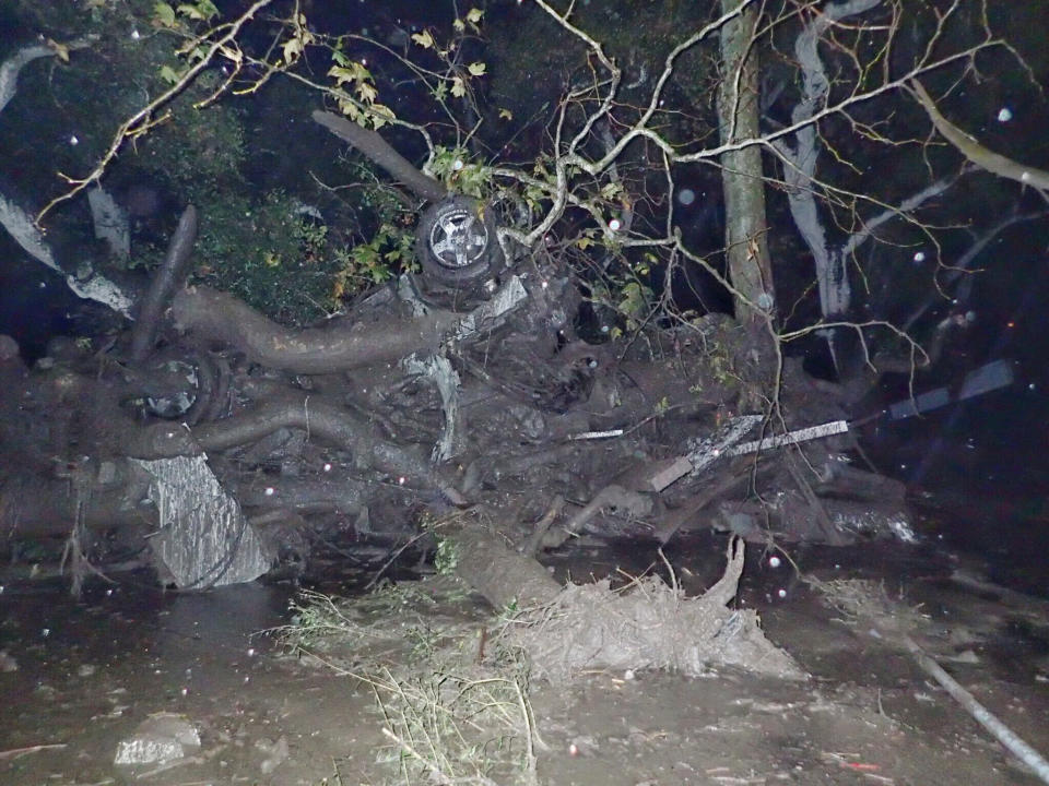 An overturned car is entangled in a tree in Montecito.