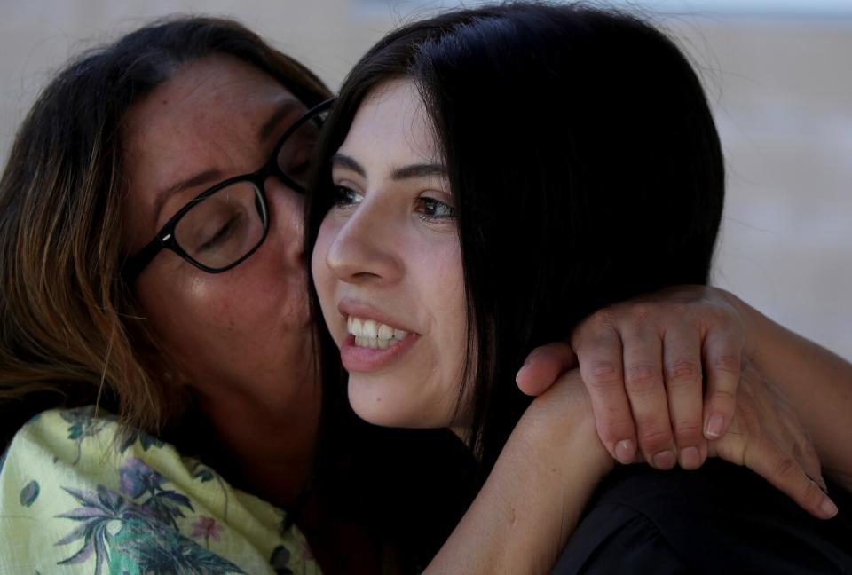 Audrie Gomez gets a kiss from her mother before graduation ceremonies.