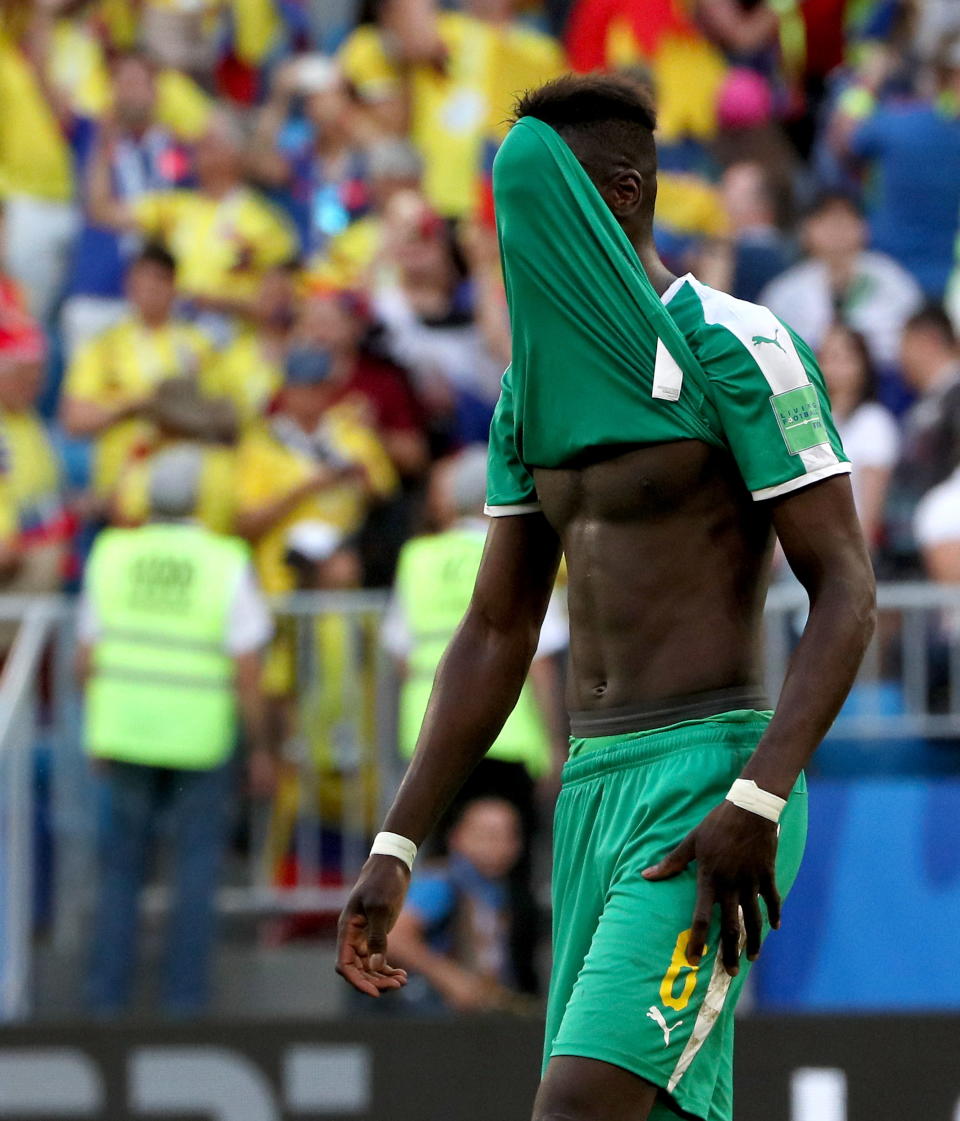 <p>Salif Sane covers his head after Senegal missed out on the knockout rounds after losing to Colombia </p>