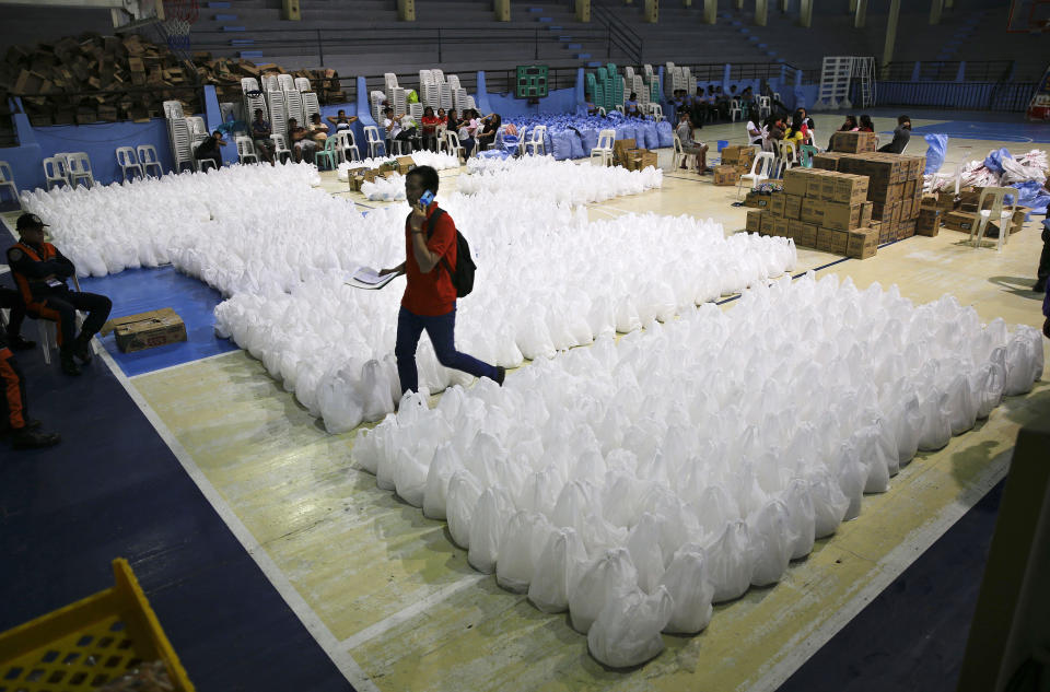 A volunteer passes by packs of relief goods as rains from Typhoon Mangkhut begin to affect Tuguegarao city, Cagayan province, northeastern Philippines on Friday, Sept. 14, 2018. Typhoon Mangkhut retained its ferocious strength and slightly shifted toward more densely populated coastal provinces on Friday as it barreled closer to the northeastern Philippines, where a massive evacuation was underway. (AP Photo/Aaron Favila)