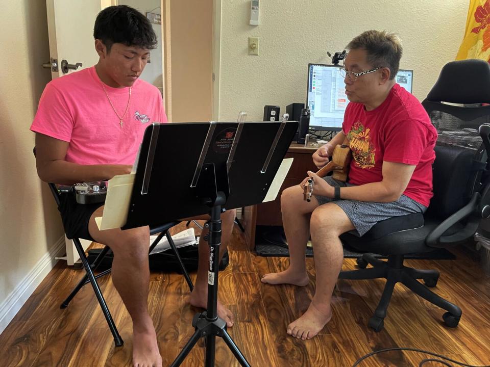 Alan Akaka teaches a high school student steel guitar.