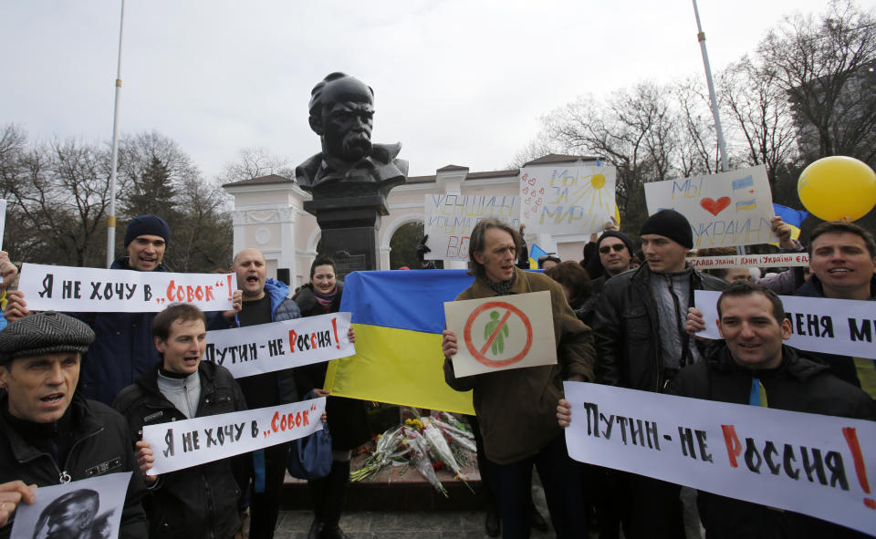 People shout slogans as they stand next to a statue of Ukrainian poet Taras Shevchenko, during a rally against the breakup of the country in Simferopol, Crimea, Ukraine, Thursday, March 9, 2014. As separatists in Crimea kept up pressure for unification with Moscow, Ukraine on Sunday solemnly commemorated the 200th anniversary of the birth of its greatest poet, with the prime minister vowing not to give up "a single centimeter" of Ukrainian territory.(AP Photo/Darko Vojinovic)