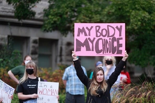 A woman holding up a sign that reads, "my body, my choice"