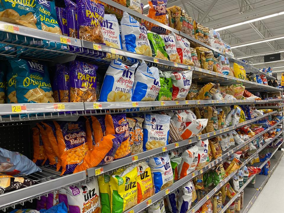 rows and shelving filled with various kinds of chip bags in a walmart