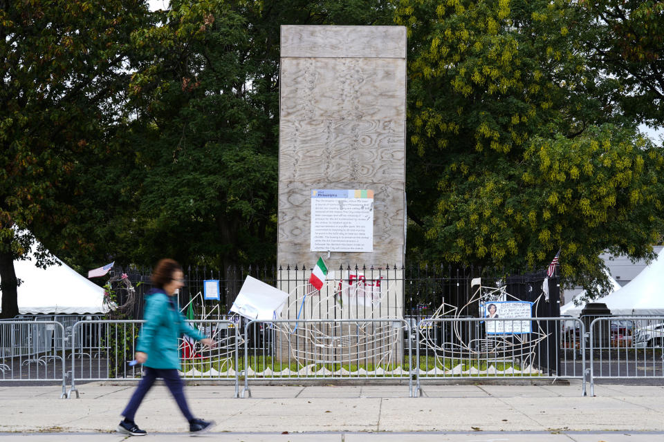 A pedestrian walks by an encased statue of Christopher Columbus at Marconi Plaza (Matt Rourke / AP file)