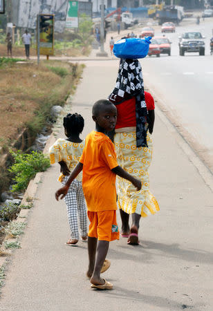 A boy follows his mother as they walk in a street after the city was taken last week by mutinous soldiers, in Bouake, Ivory Coast January 13, 2017. REUTERS/Thierry Gouegnon