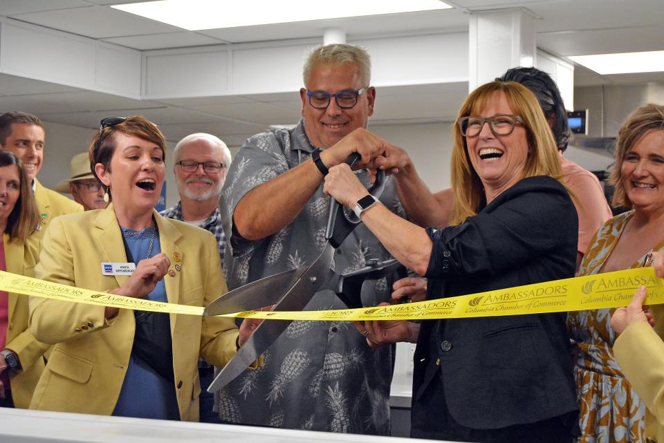 The Loop Community Improvement District Board President James Roark Gruender and Executive Director Carrie Gartner prepare to cut the ribbon Thursday on the ComoCooks shared kitchen space at 14 Business Loop 70 E.