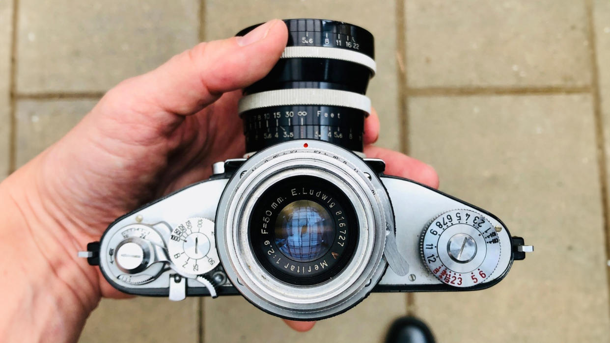  Photographer holding an Exakta V with Magnifying Finder, showing off its magnifying chimney finder. 