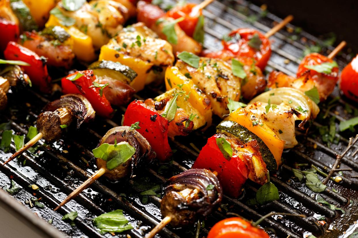 Focus on five roasted vegetable skewers in a herb marinade on a stovetop grill pan