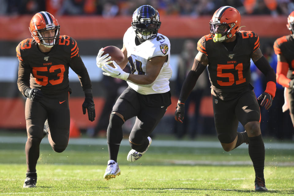 FILE - In this Sunday, Dec. 22, 2019, file photo, Baltimore Ravens running back Mark Ingram (21) rushes after a catch under pressure from Cleveland Browns middle linebacker Joe Schobert (53) and linebacker Mack Wilson (51) during the first half of an NFL football game, in Cleveland. Ingram intends to cap a decade of bullish carries up the middle by helping the Baltimore Ravens break their own single-season record of 3,296 yards rushing. (AP Photo/David Richard, File)