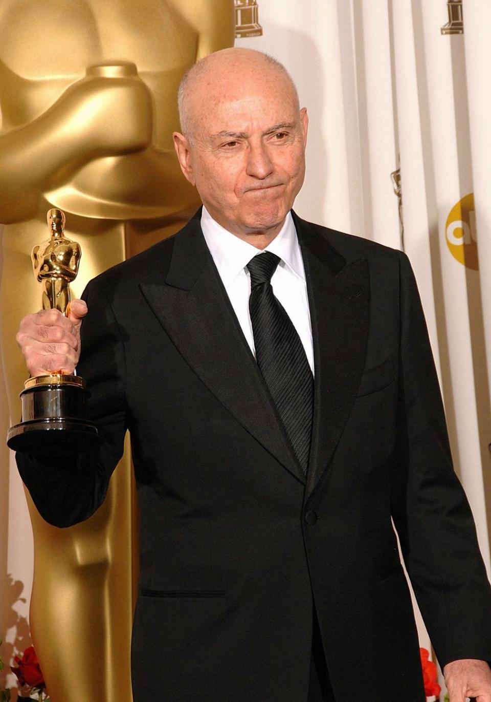 alan arkin wearing a black suit and holding an oscar