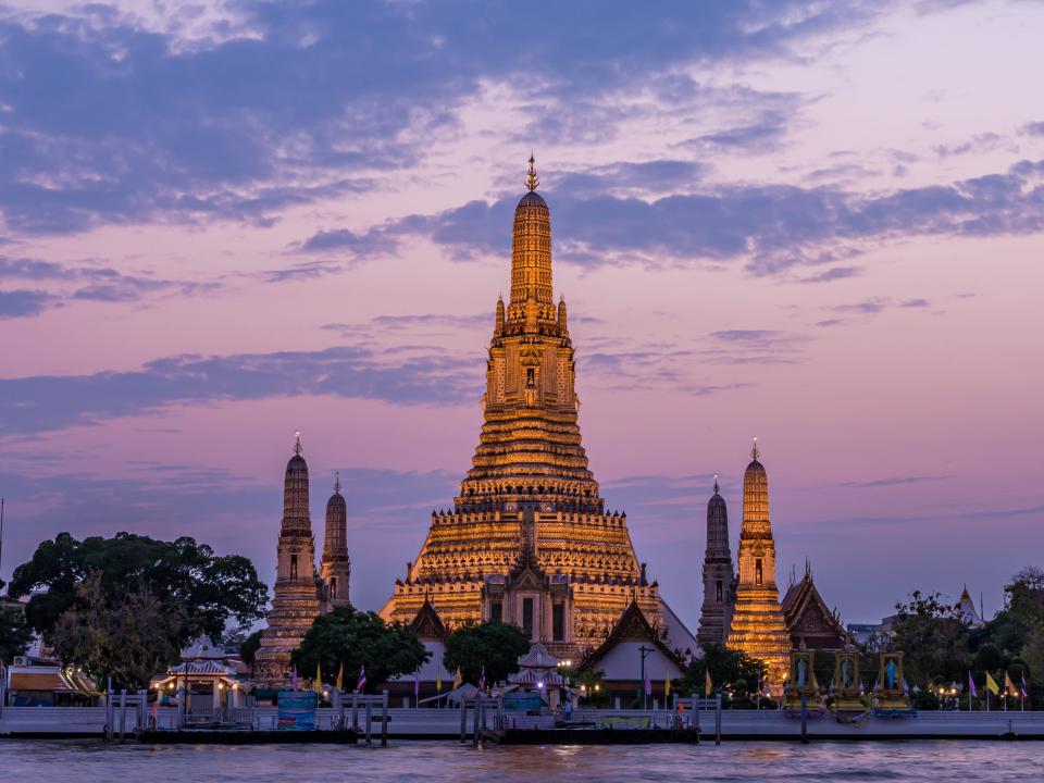 Wat Arun Temple beside Chao Phraya River at twilight time in Bangkok, Thailand.