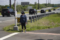 A woman wears a mask as she waits for the motorcade for President Donald Trump to go past, Saturday, May 23, 2020, in Sterling, Va. Trump is en route to Trump National Golf Club. (AP Photo/Alex Brandon)