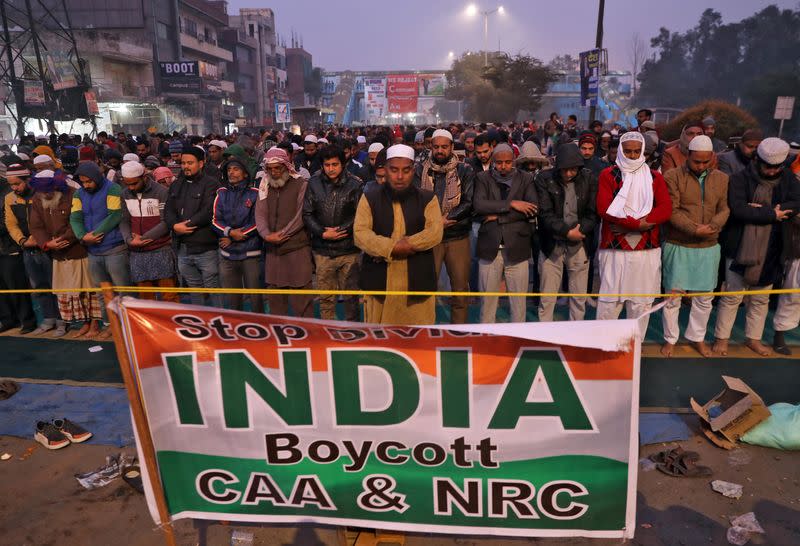 Local residents offer prayers on a road during a protest against a new citizenship law, in New Delhi