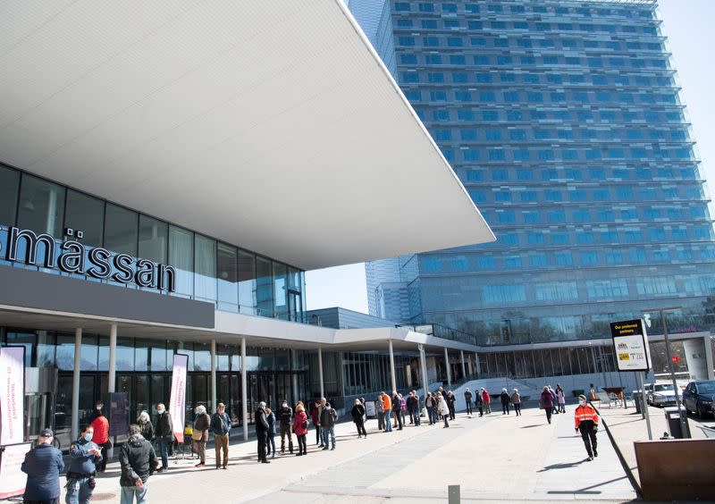 FILE PHOTO: People stand in line to get a COVID-19 vaccine outside the Stockholmsmassan exhibition center, in Stockholm