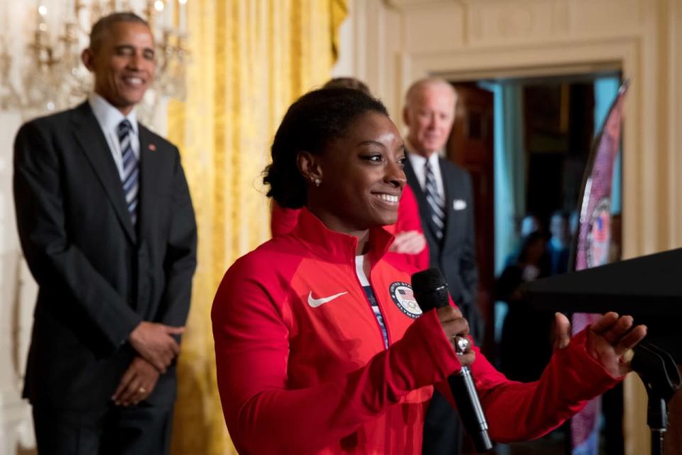 <p>US Olympics gymnast Simone Biles, center, accompanied by President Barack Obama, and Vice President Joe Biden, speaks in the East Room of the White House in Washington, Thursday, Sept. 29, 2016, during a ceremony where President Barack Obama honored members of the 2016 United States Summer Olympic and Paralympic Teams. (AP Photo/Andrew Harnik)</p>