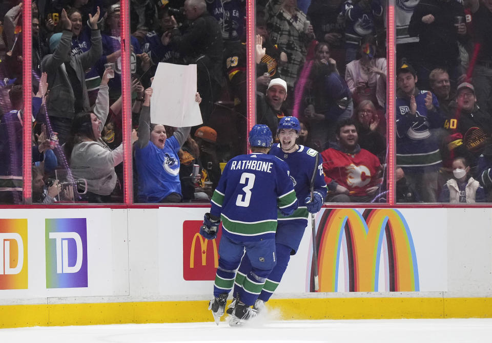 Vancouver Canucks' Aidan McDonough, back, and Jack Rathbone celebrate McDonough's goal against the Calgary Flames during the second period of an NHL hockey game Friday, March 31, 2023, in Vancouver, British Columbia. (Darryl Dyck/The Canadian Press via AP)