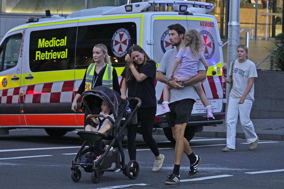 People are led out from the Westfield Shopping Centre where multiple people were stabbed in Sydney, Saturday, April 13, 2024. A man stabbed six people to death at the busy Sydney shopping center Saturday before he was fatally shot, police said. (AP Photo/Rick Rycroft)