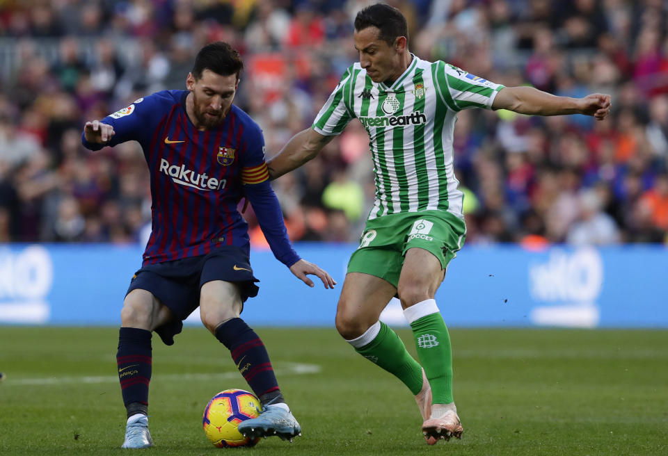 FC Barcelona's Lionel Messi, left, duels for the ball against Betis' Andres Guardado during the Spanish La Liga soccer match between FC Barcelona and Betis at the Camp Nou stadium in Barcelona, Spain, Sunday, Nov. 11, 2018. (AP Photo/Manu Fernandez)