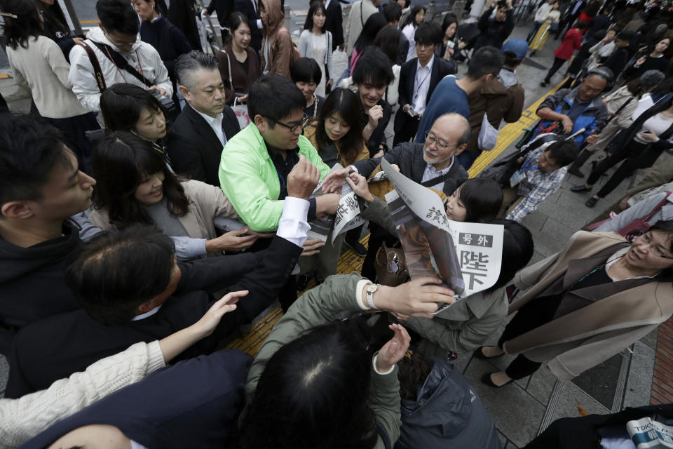 A Yomiuri newspaper worker hands a copy of the extra edition reporting the enthronement ceremony for the 59-year-old Emperor Naruhito Tuesday, Oct. 22, 2019, in Tokyo, Japan. (AP Photo/Aaron Favila)