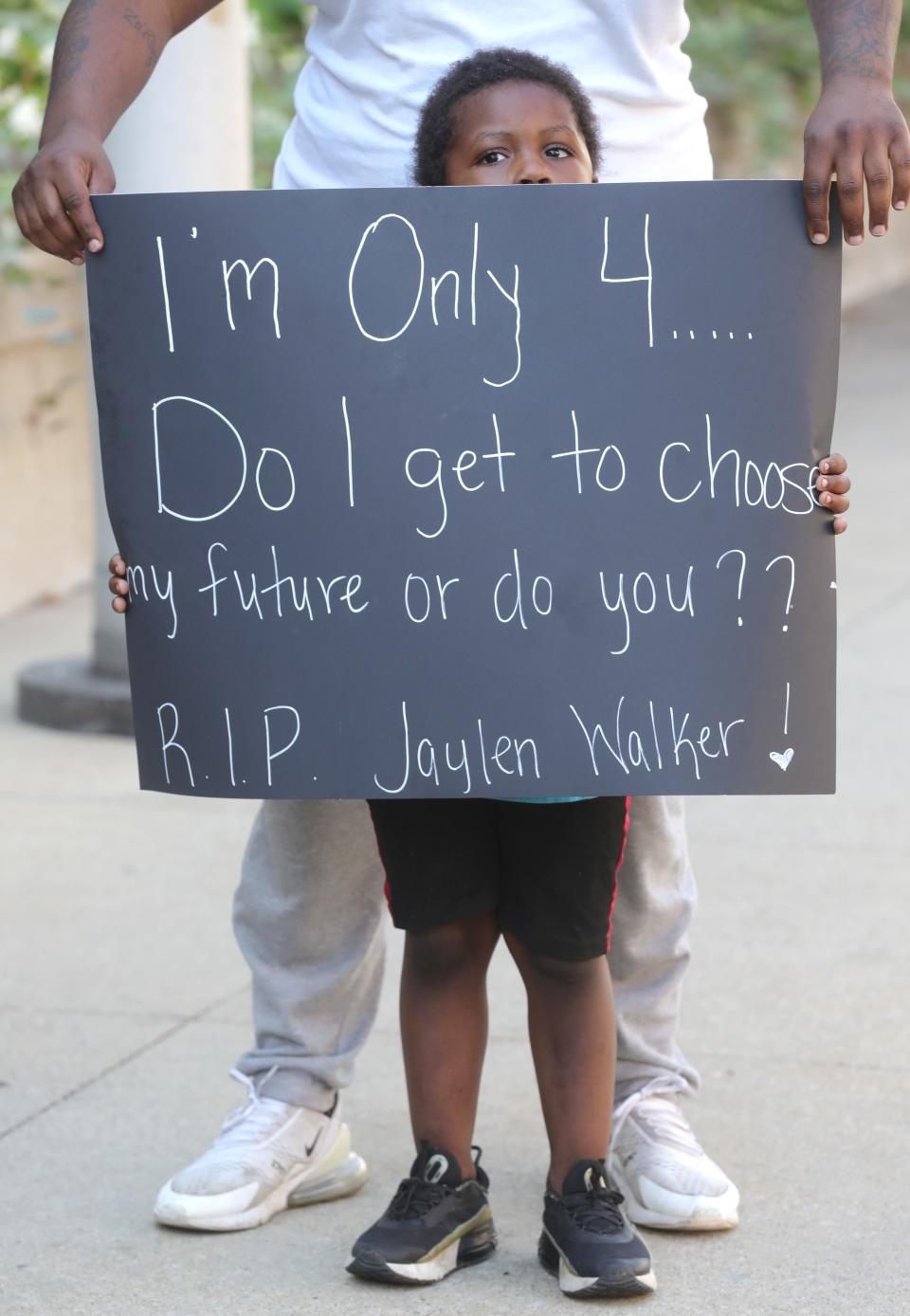 Tywan Junius III holds a sign with help from his father, Tywan Junius II, during a protest Thursday in front of the Stubbs Justice Center in Akron.