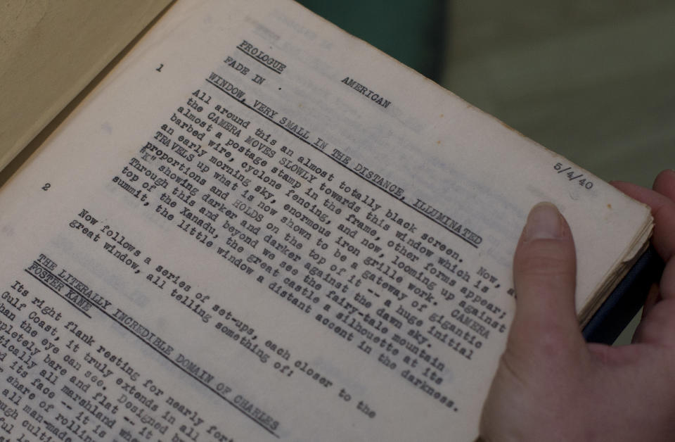 The front page of the then originally titled 'American' (seen at top),or as it is now known 'Citizen Kane' film which was Orson Well working copy of the script held by an employee of Sotheby's auction house in London, Thursday, Feb. 27, 2014. Orson Welles' personal draft script for "Citizen Kane" is up for sale _ from the collection of an American almost as wealthy as the movie's monstrous newspaper mogul, though considerably more private. The script, which has an estimated price of 15,000 pounds to 20,000 pounds ($25,000 to $33,000), is part of a sale of more than 1,000 items owned by the late Stanley Seeger, an affluent collector of everything from Old Masters and contemporary art to historical oddities.(AP Photo/Alastair Grant)