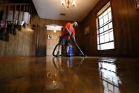 Dalton Hamilton vacuums a flood damaged floor inside a friend's house in St. Amant, Louisiana. REUTERS/Jonathan Bachman