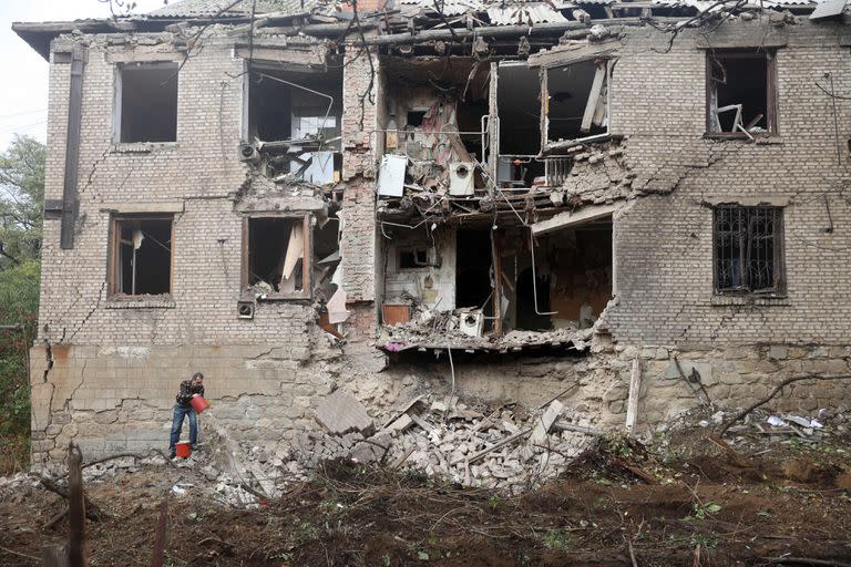 Un residente local limpia los escombros junto a un edificio residencial destruido por un ataque con misiles en Konstantinovka, en la región oriental de Donetsk, el 14 de octubre de 2022.