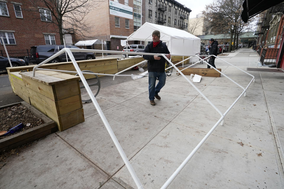 Wade Hagenbart lifts plastic piping for a tent while building a winter shelter for patrons of Guero's, the popular taco and margarita restaurant he co-owns in Brooklyn's Prospect Heights neighborhood, Wednesday, Dec. 2, 2020, in New York. (AP Photo/Kathy Willens)