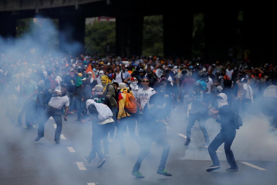 <p>Manifestantes en medio del gas lacrimógeno disparado por las fuerzas de seguridad durante la manifestación en Caracas este 6 de abril, 2016. REUTERS/Carlos Garcia Rawlins</p>